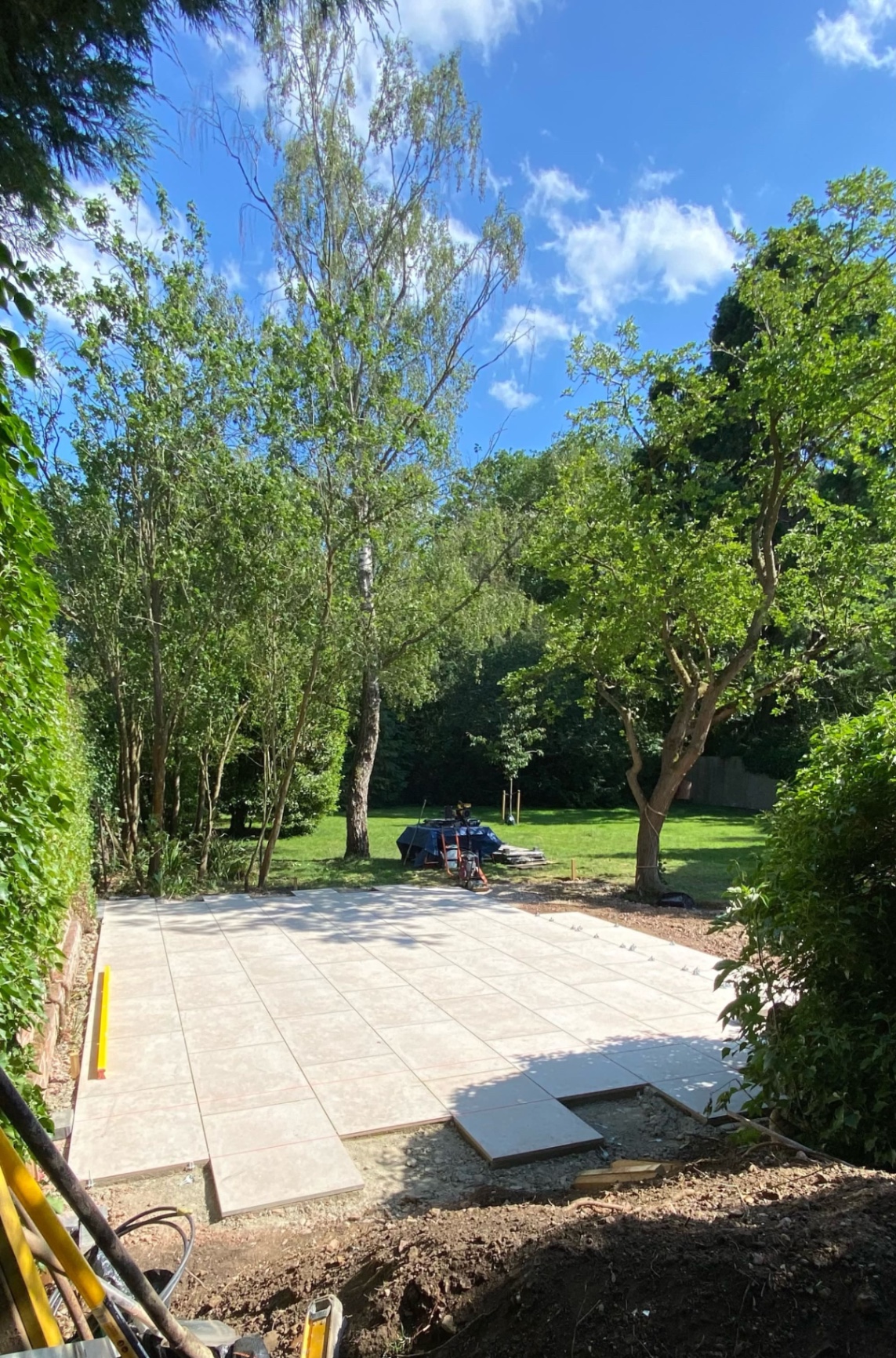 Finished porcelain patio in a Godmanchester garden near Huntingdon, looking out across the lawn to mature trees - the completed 56m² bespoke build by Arcadia Build & Landscape