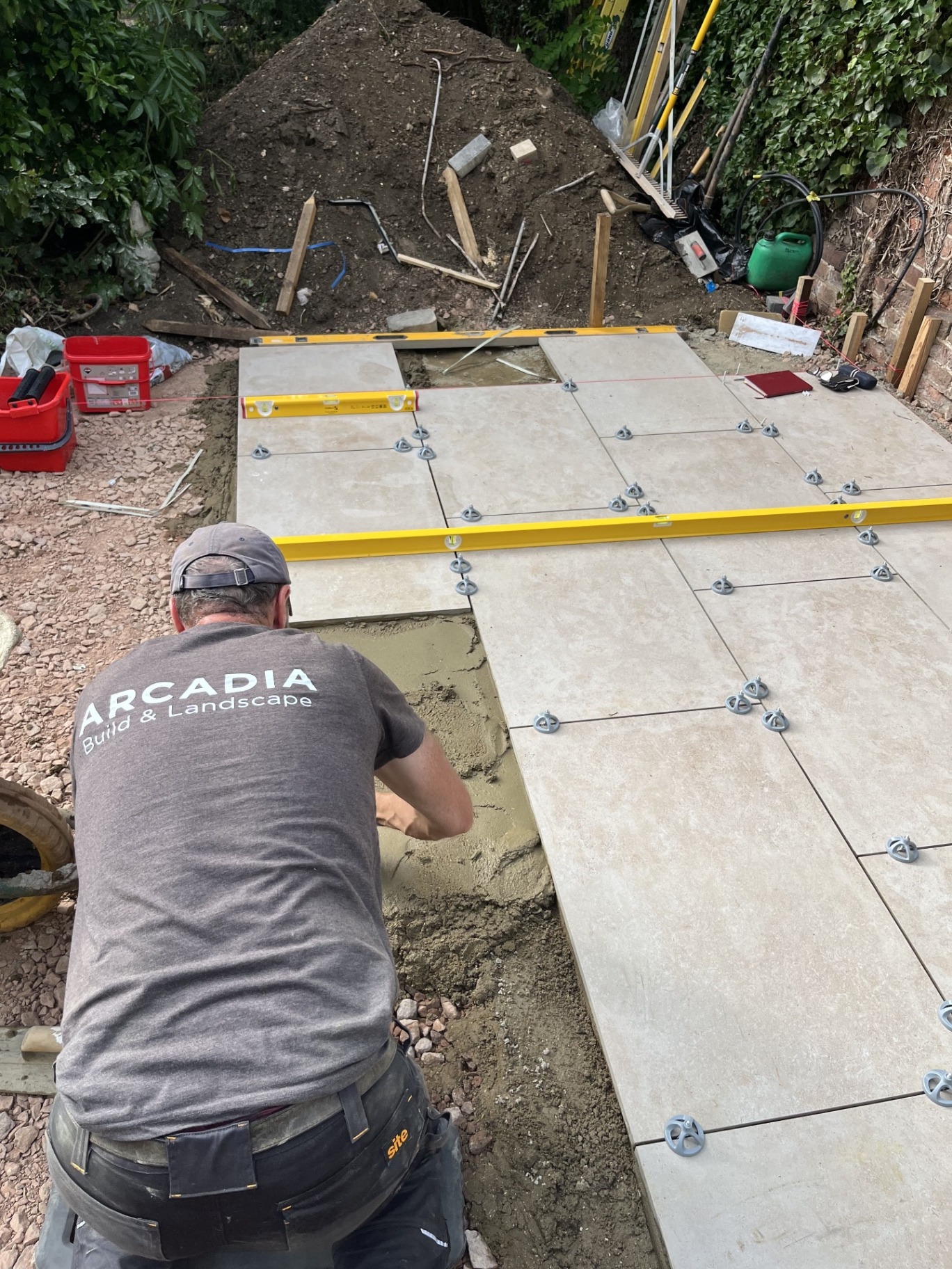 Large-format porcelain slabs being carefully levelled with spacers and straight edges to keep the laying lines precise across the patio