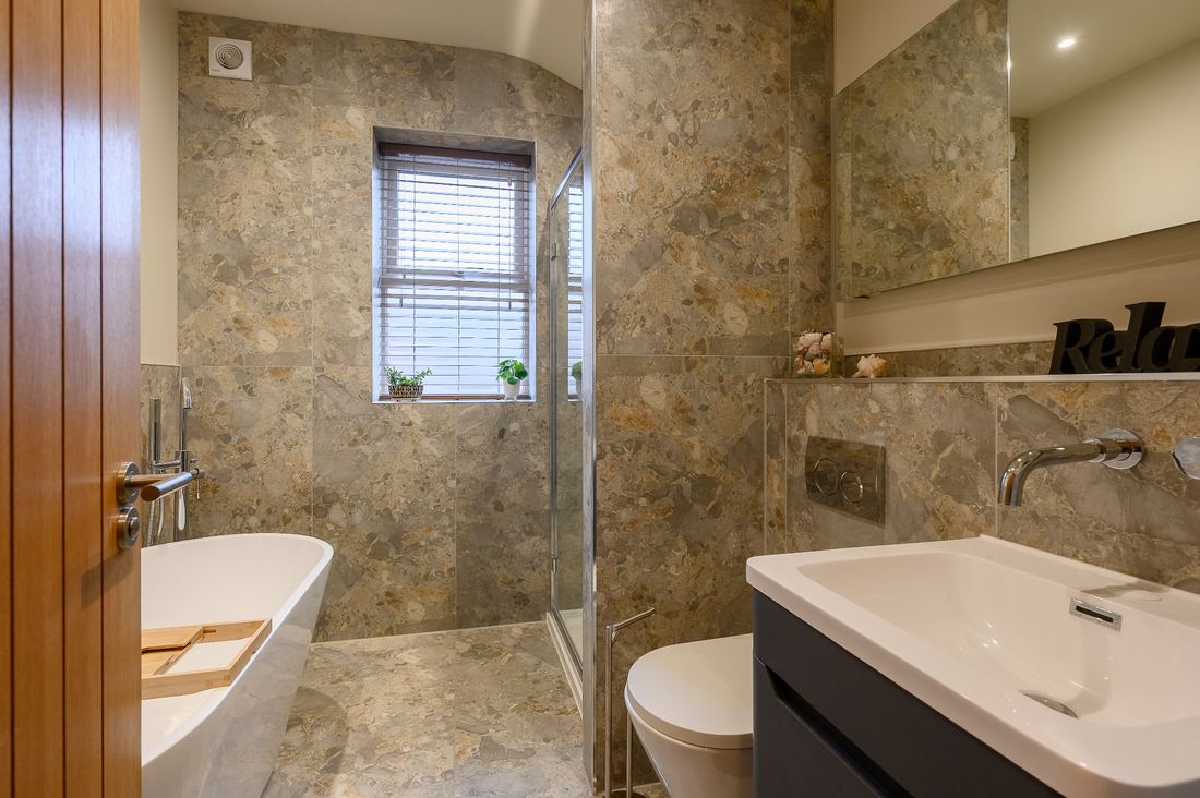Luxury bathroom renovation with natural stone tiles and freestanding bath by builder in Cambridgeshire