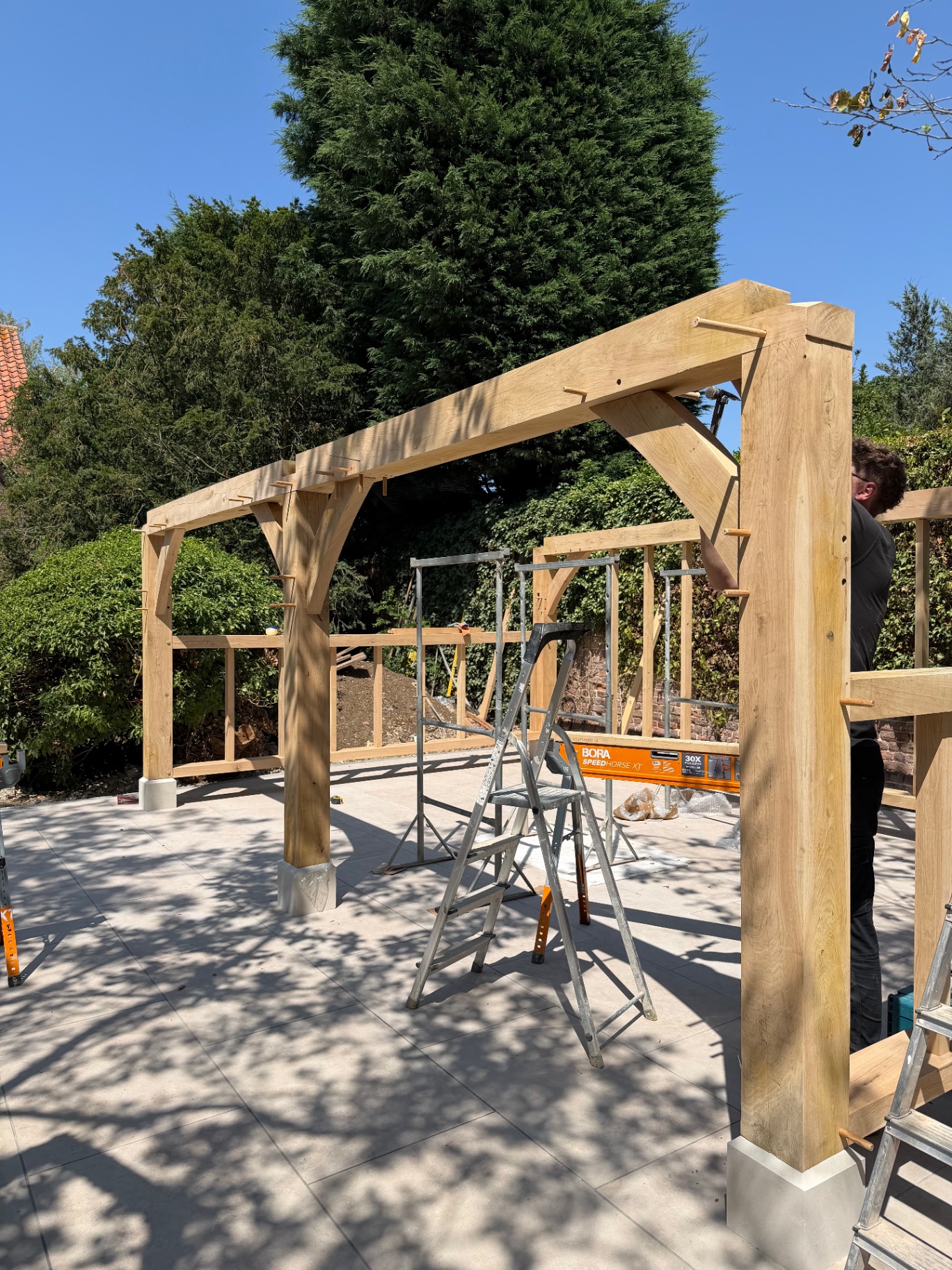 Landscaper pegging the oak gazebo frame joints together in Godmanchester, Cambridgeshire