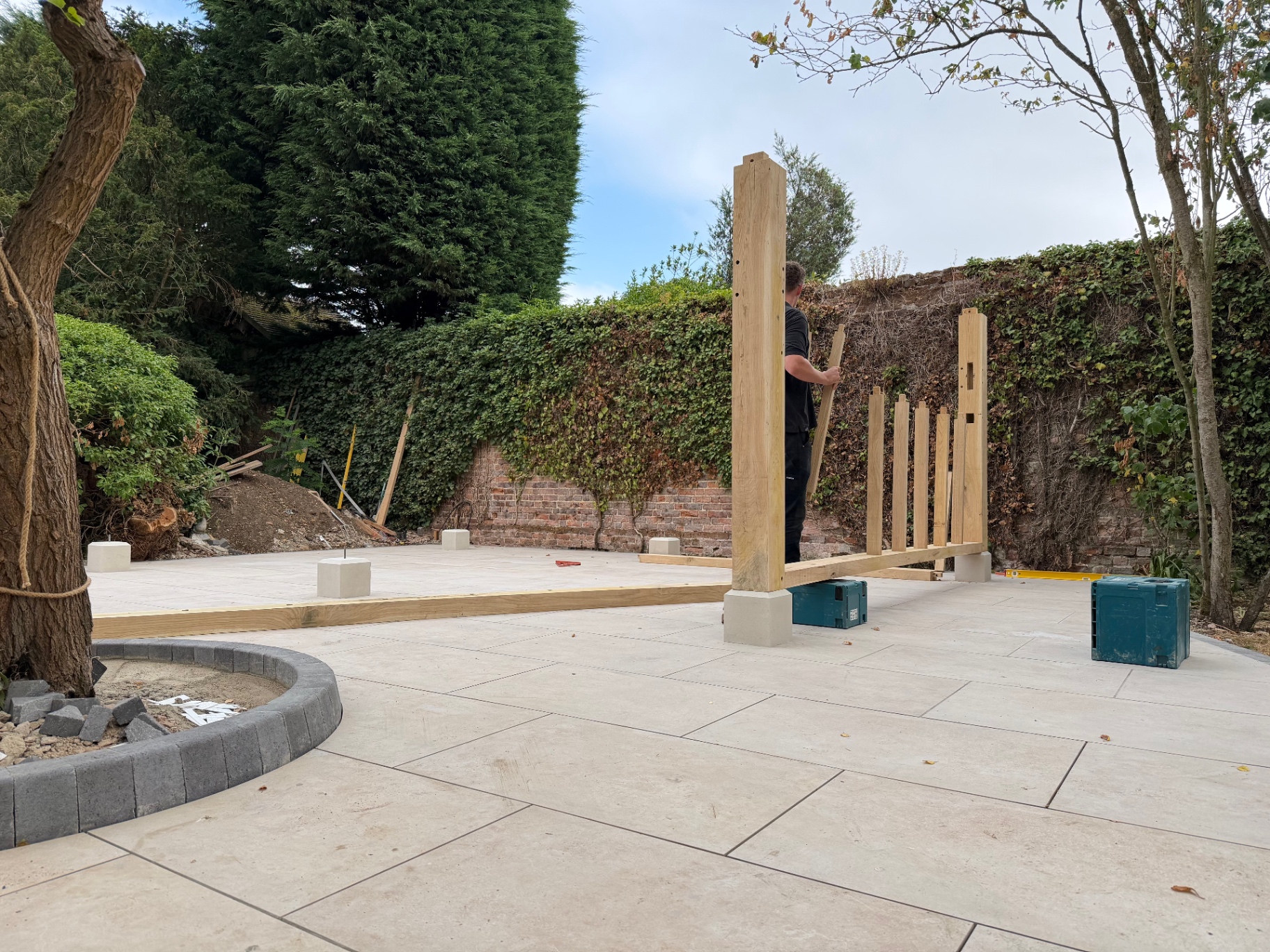 First oak gazebo post being stood on its padstone on the new patio in Godmanchester