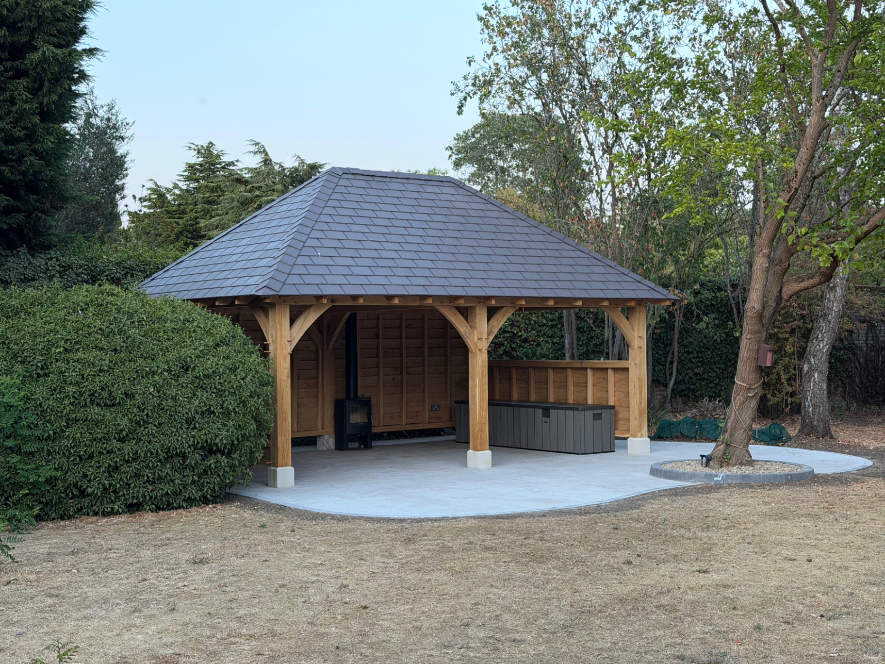 Finished porcelain patio beneath a hand-built oak gazebo with slate roof in Godmanchester, Cambridgeshire