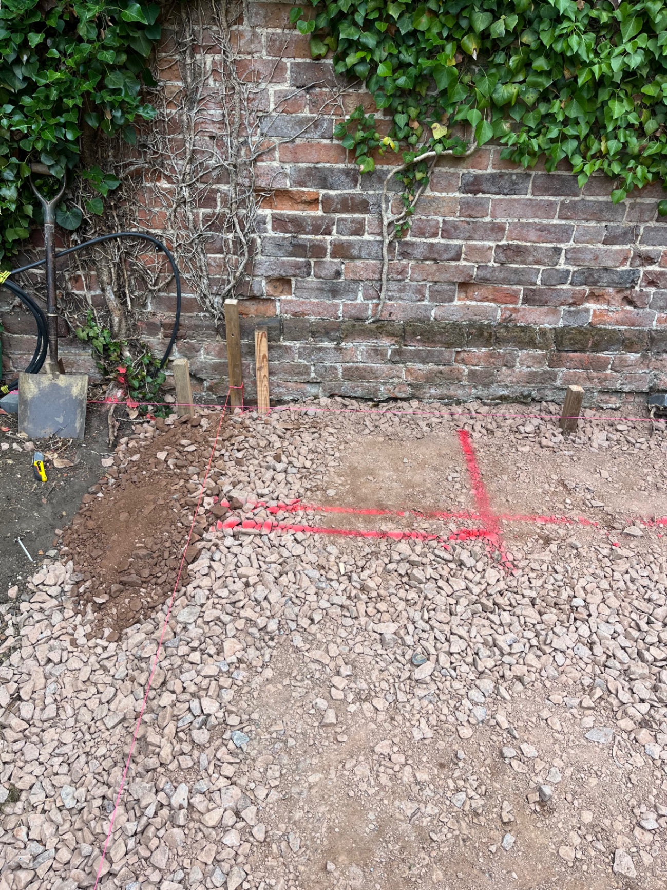 Close up of setting out lines and timber pegs against the brick wall in Godmanchester