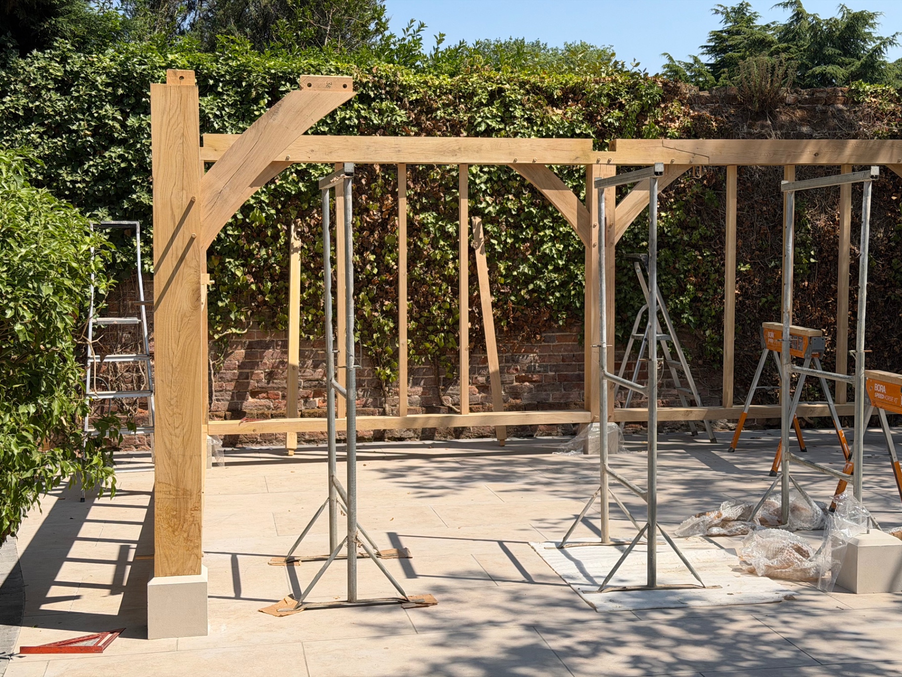 Oak gazebo frame taking shape with braced beams on the porcelain patio in Godmanchester