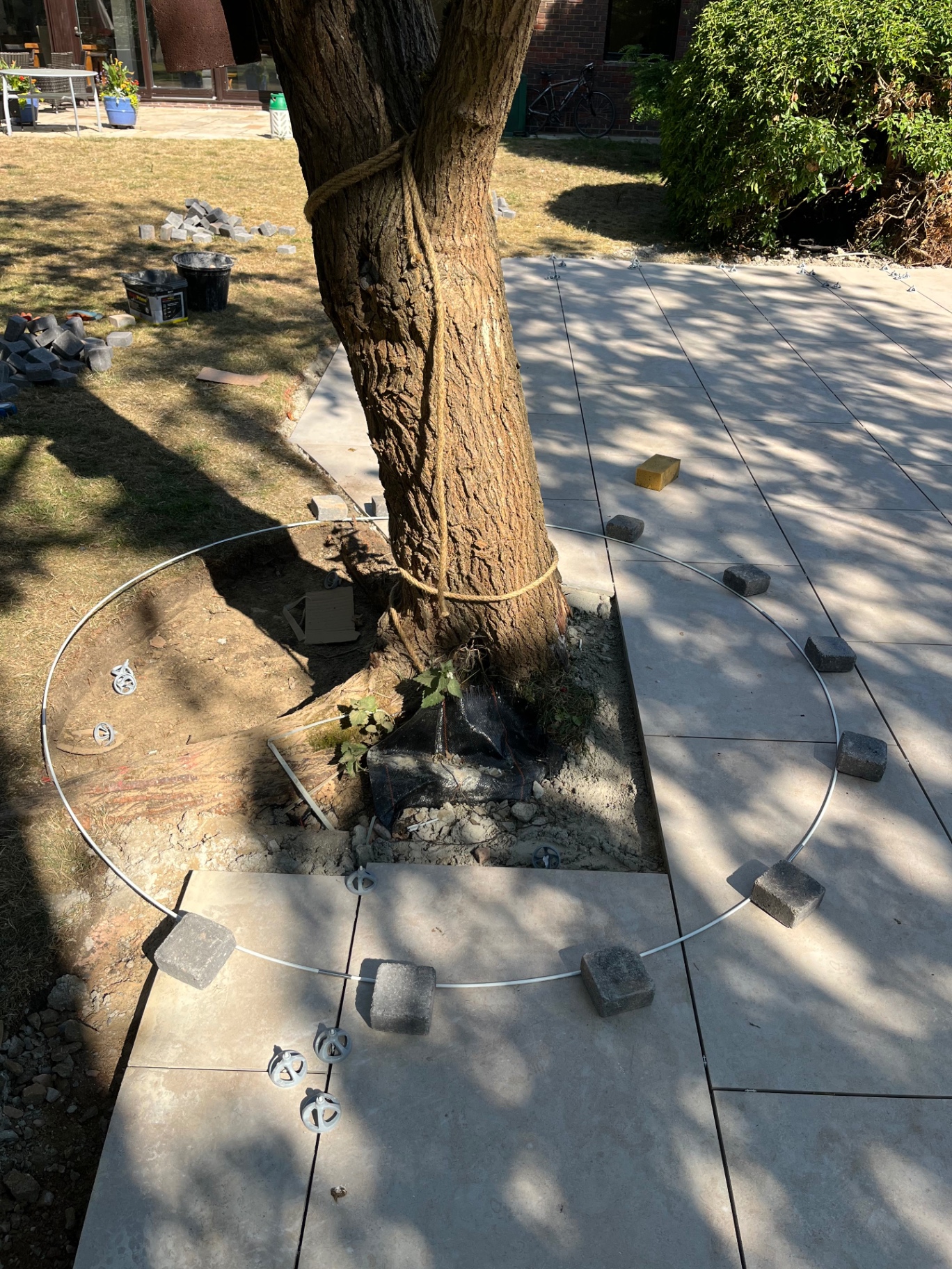 Circular cut out formed around a mature tree within the porcelain patio in Godmanchester