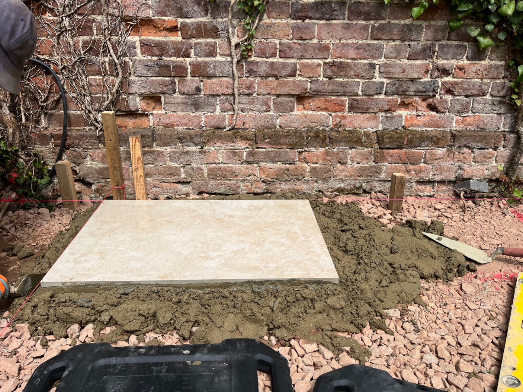 First porcelain slab bedded onto a full mortar bed beside the brick wall in Godmanchester