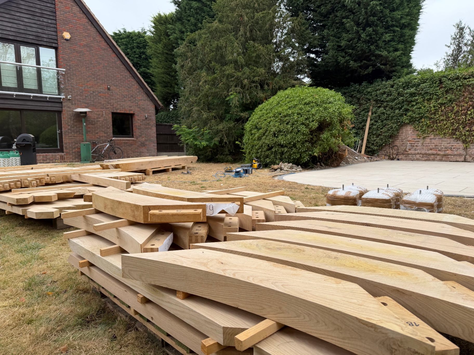 Stack of green oak beams and rafters delivered on pallets for the gazebo in Godmanchester