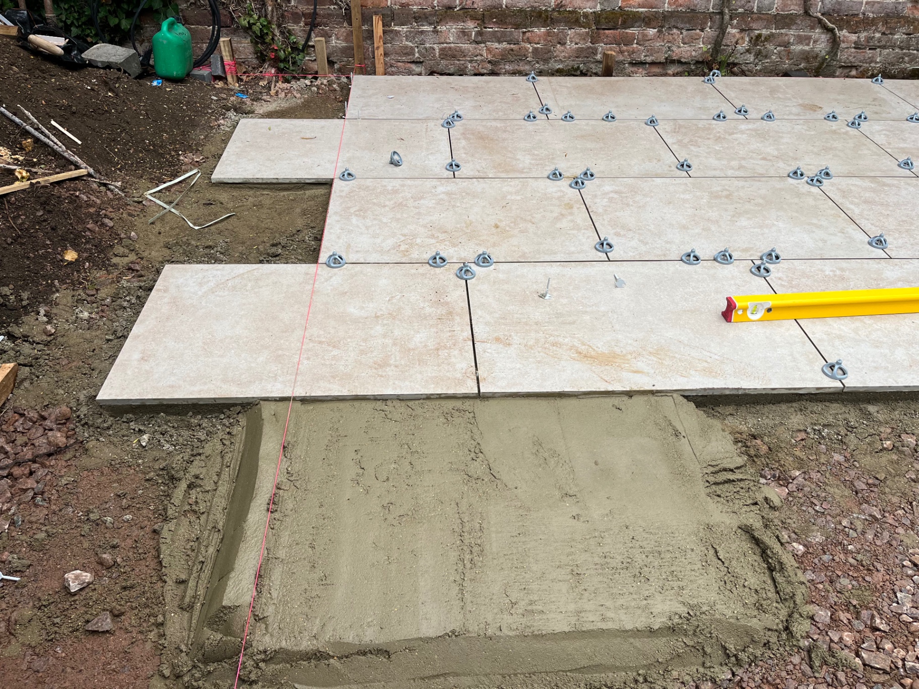Porcelain paving spreading across the garden with a spirit level checking the falls in Godmanchester