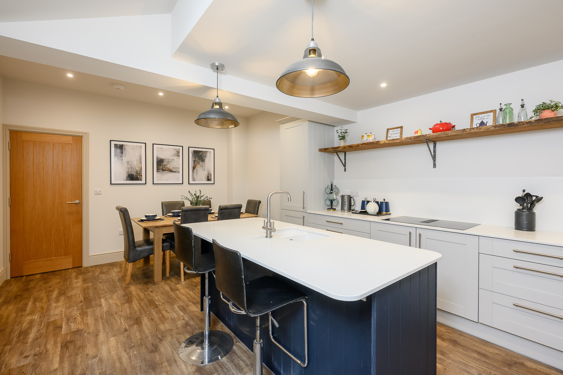 Open plan kitchen diner with dining table, island seating and live-edge oak shelf in Cambridgeshire