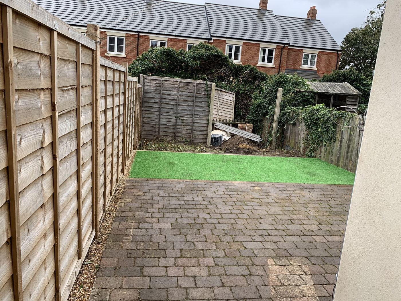 Finished Bedford rear garden with professionally installed artificial grass and clean borders by Arcadia Build & Landscape