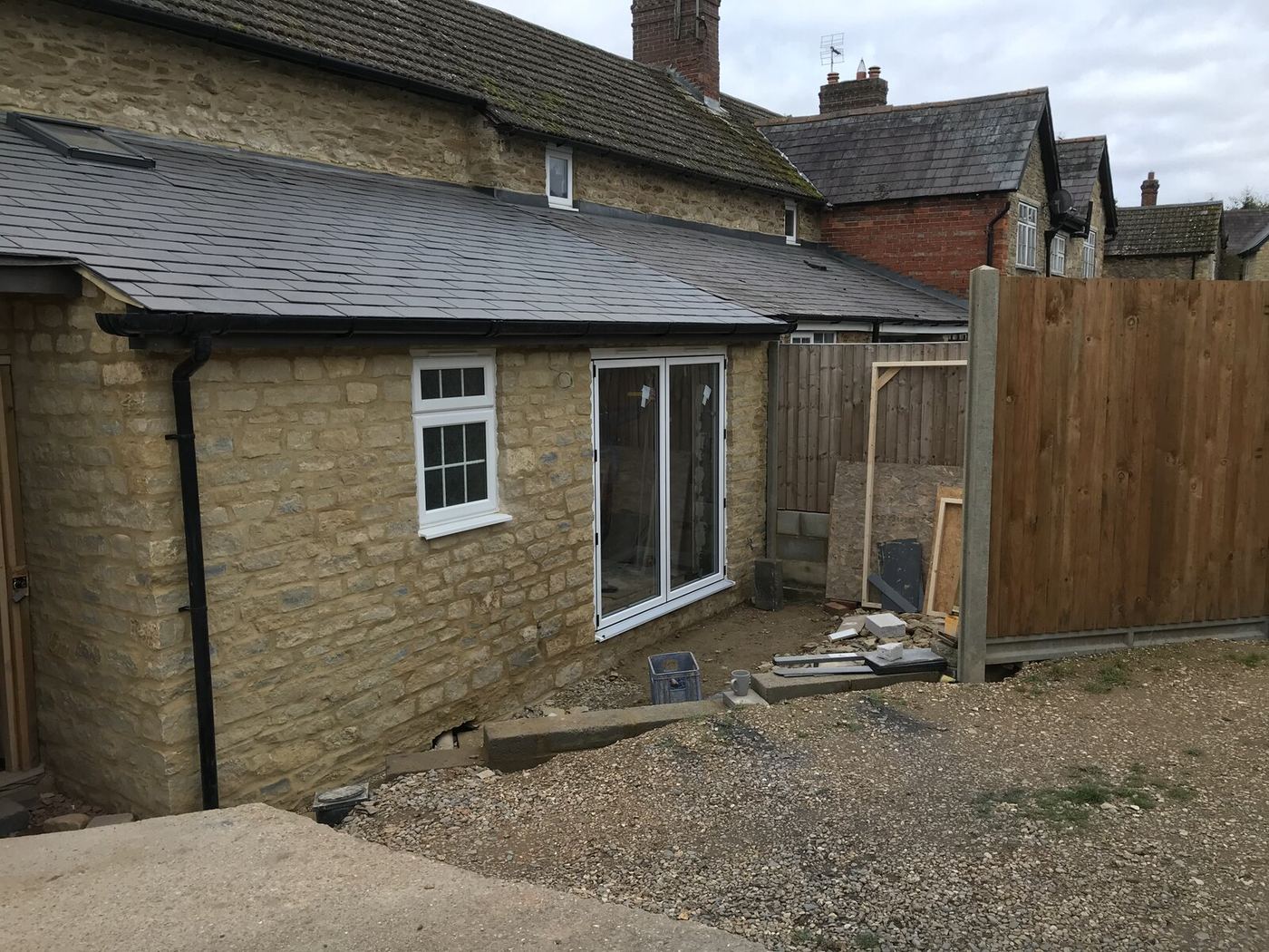 Turvey stone cottage rear extension with slate roof, Velux skylights and new bifold doors by Arcadia Build & Landscape