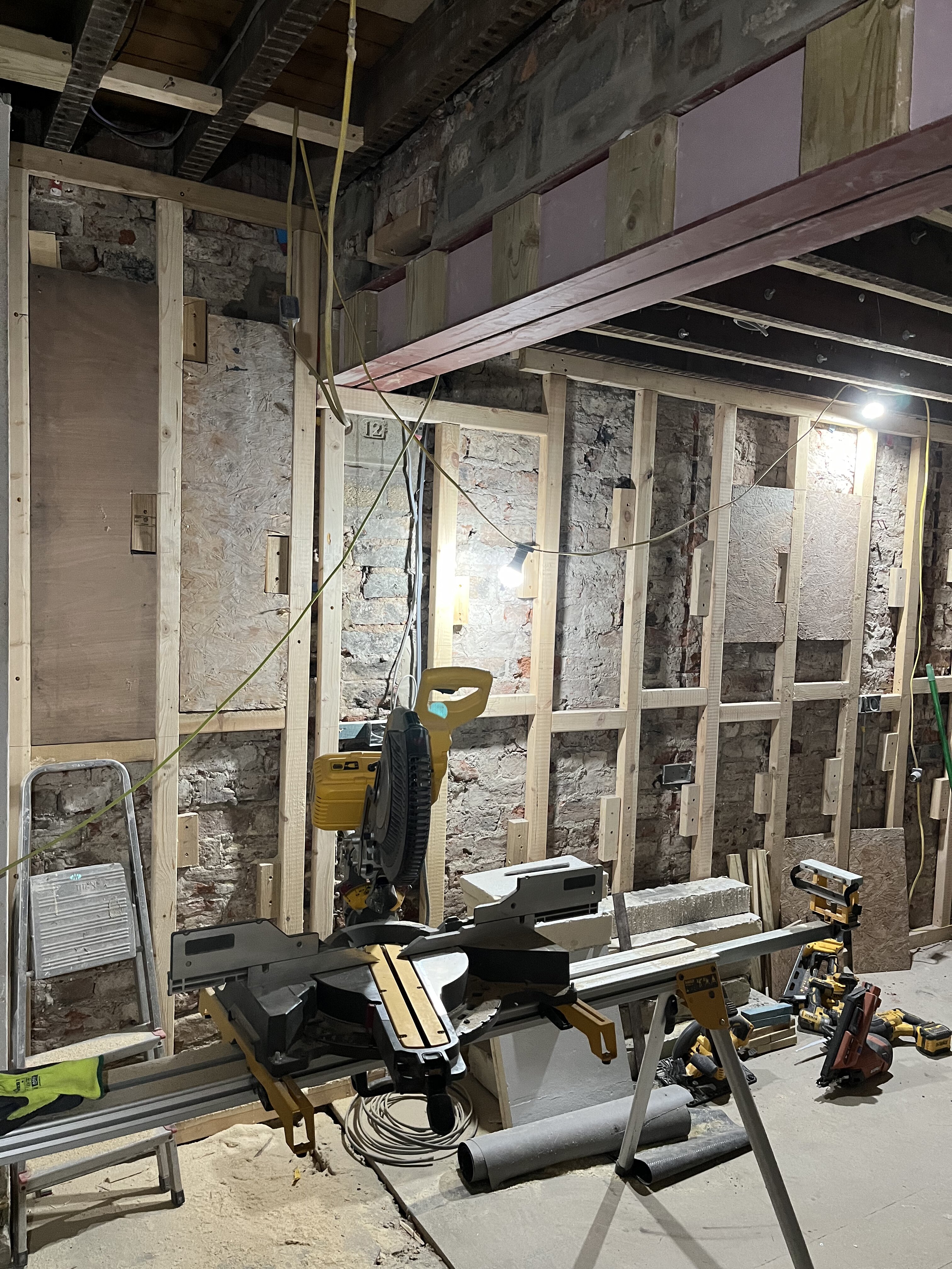 Internal timber stud framing fixed to original brick wall in Cambridgeshire renovation
