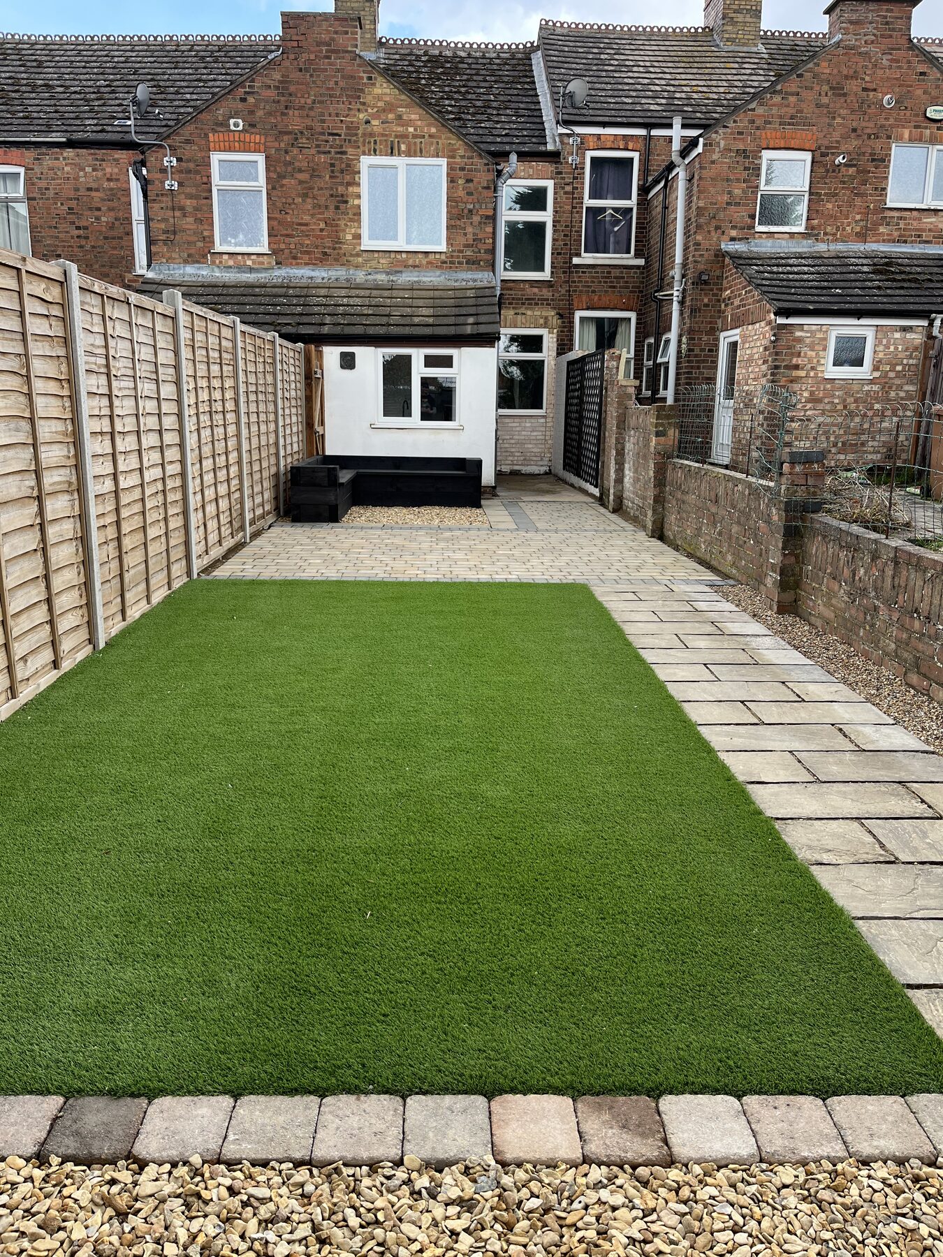 Finished block paving patio with charcoal border, artificial grass lawn and new fencing in Fletton, Peterborough