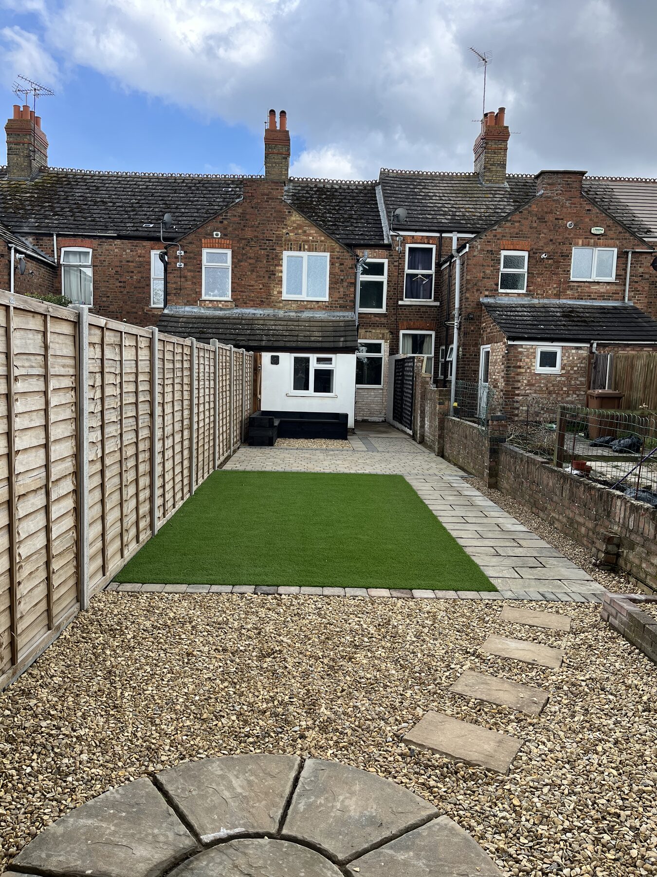 Artificial grass lawn framed by block paving and gravel in Fletton, Peterborough garden