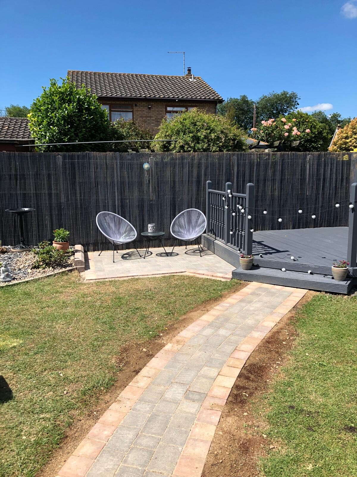 Sun-soaked block-paved seating area with chairs and new fencing in Folksworth, Cambridgeshire