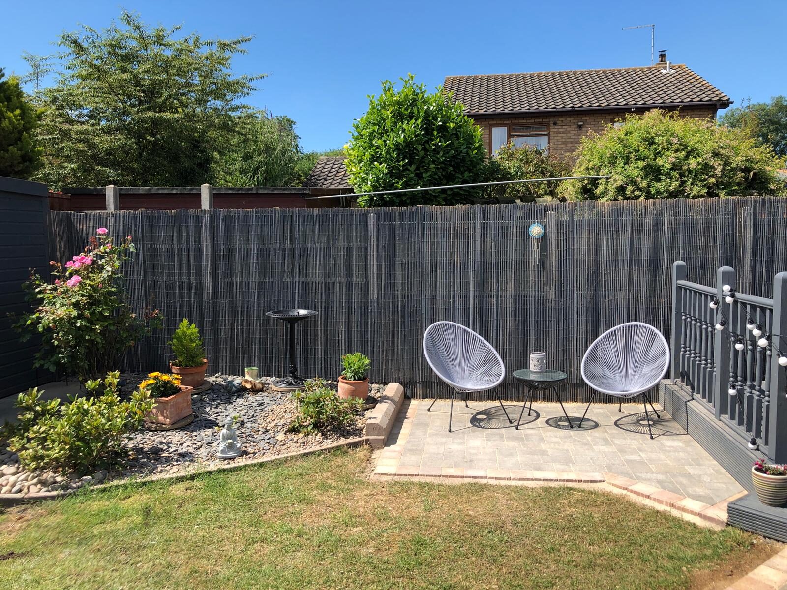 Block-paved patio with seating area, gravel bed and roses in Folksworth, Cambridgeshire