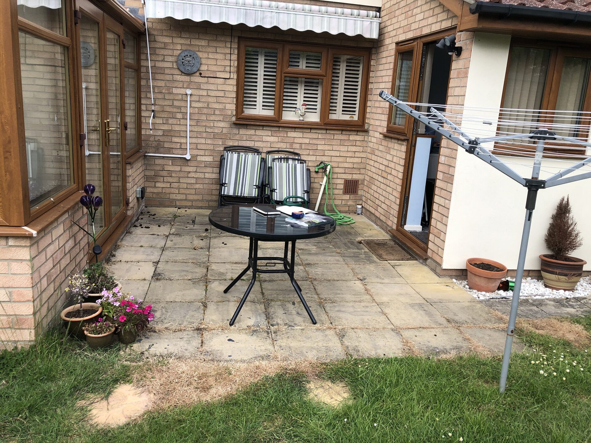 Old weathered concrete slab patio outside conservatory in Folksworth, Cambridgeshire before renovation