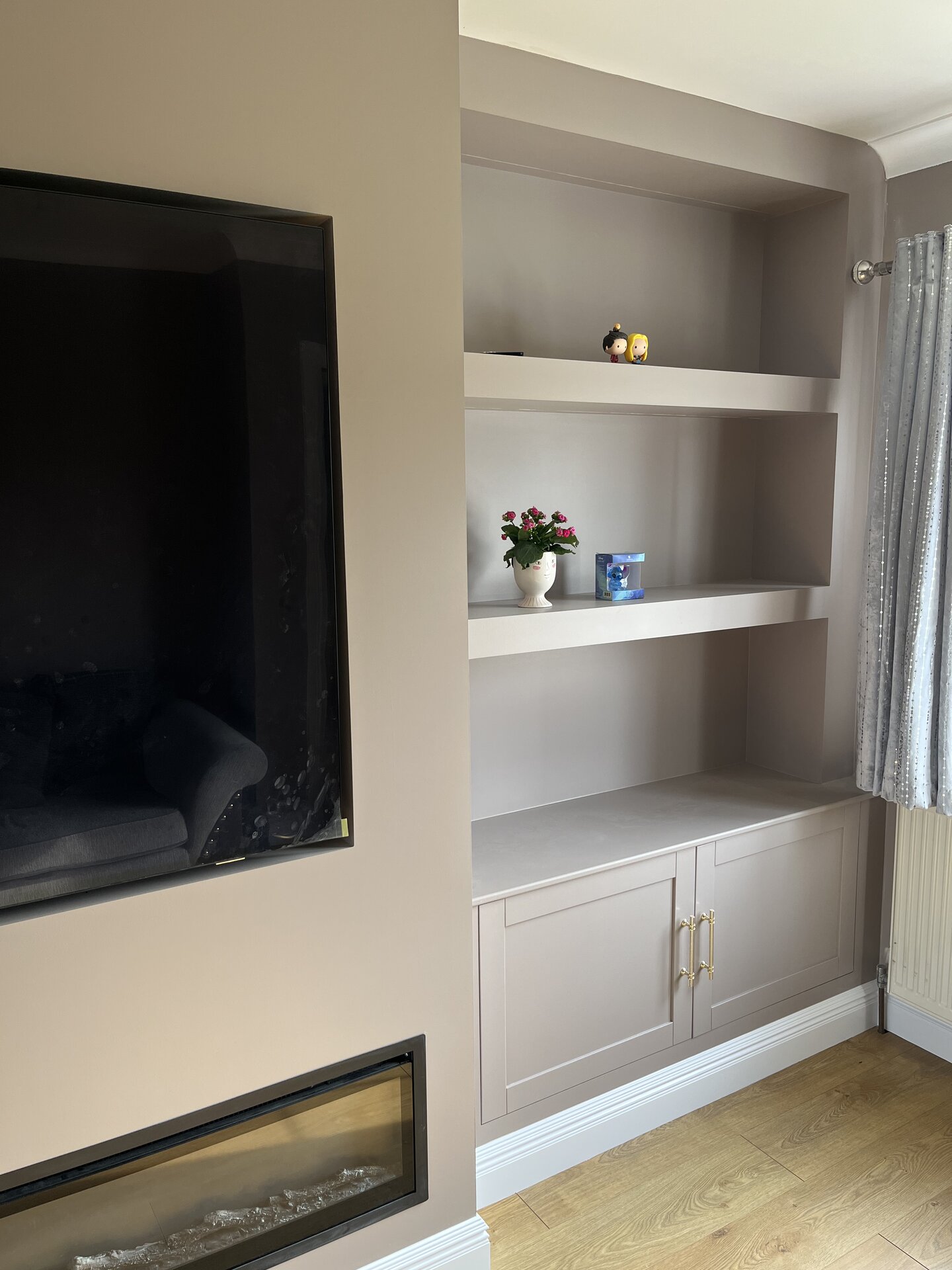 Close-up of bespoke painted alcove shelving and Shaker cabinets with brass handles in Sawtry