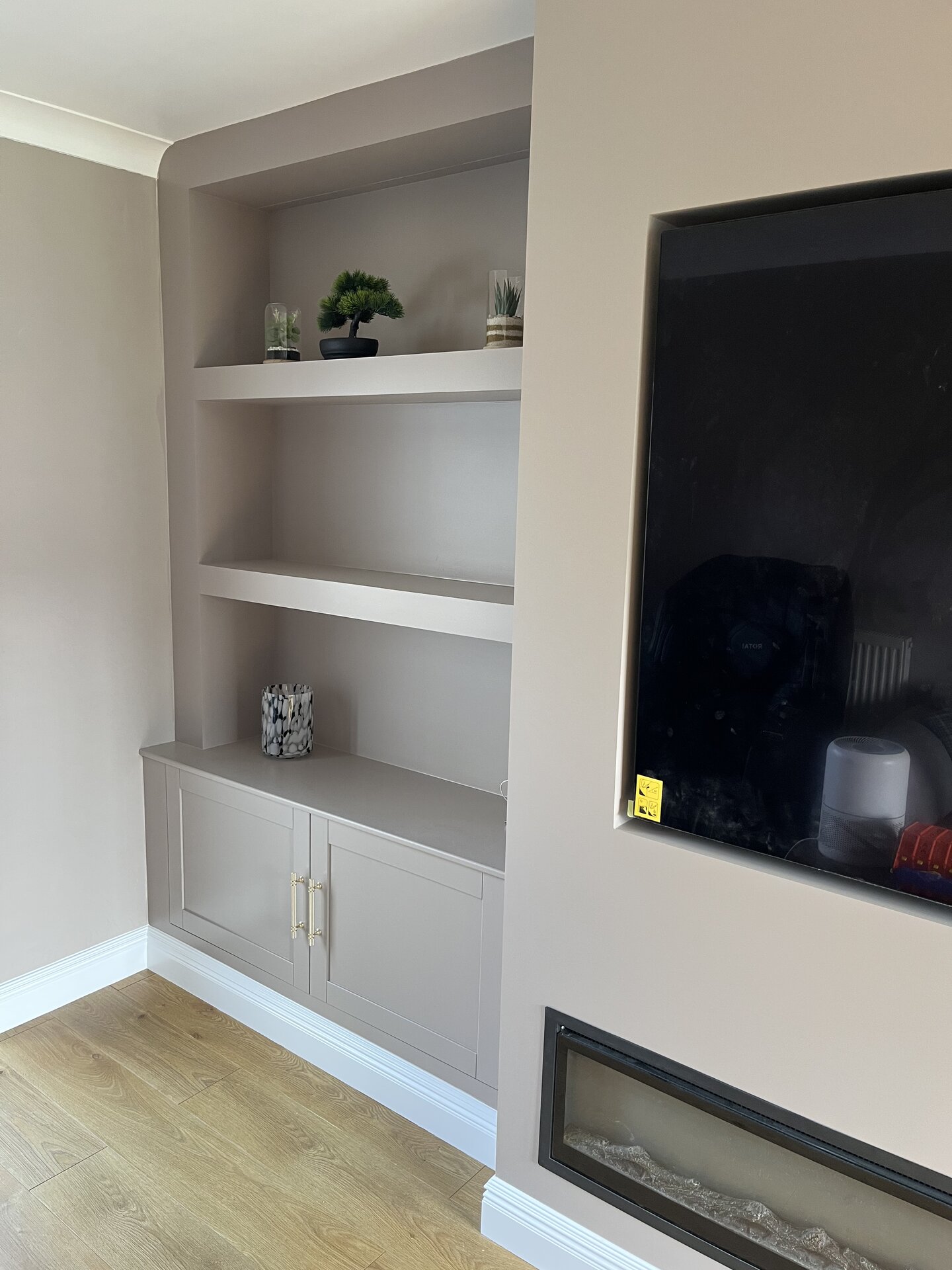 Opposite alcove cabinet styled with planters beside the bespoke media wall in Sawtry