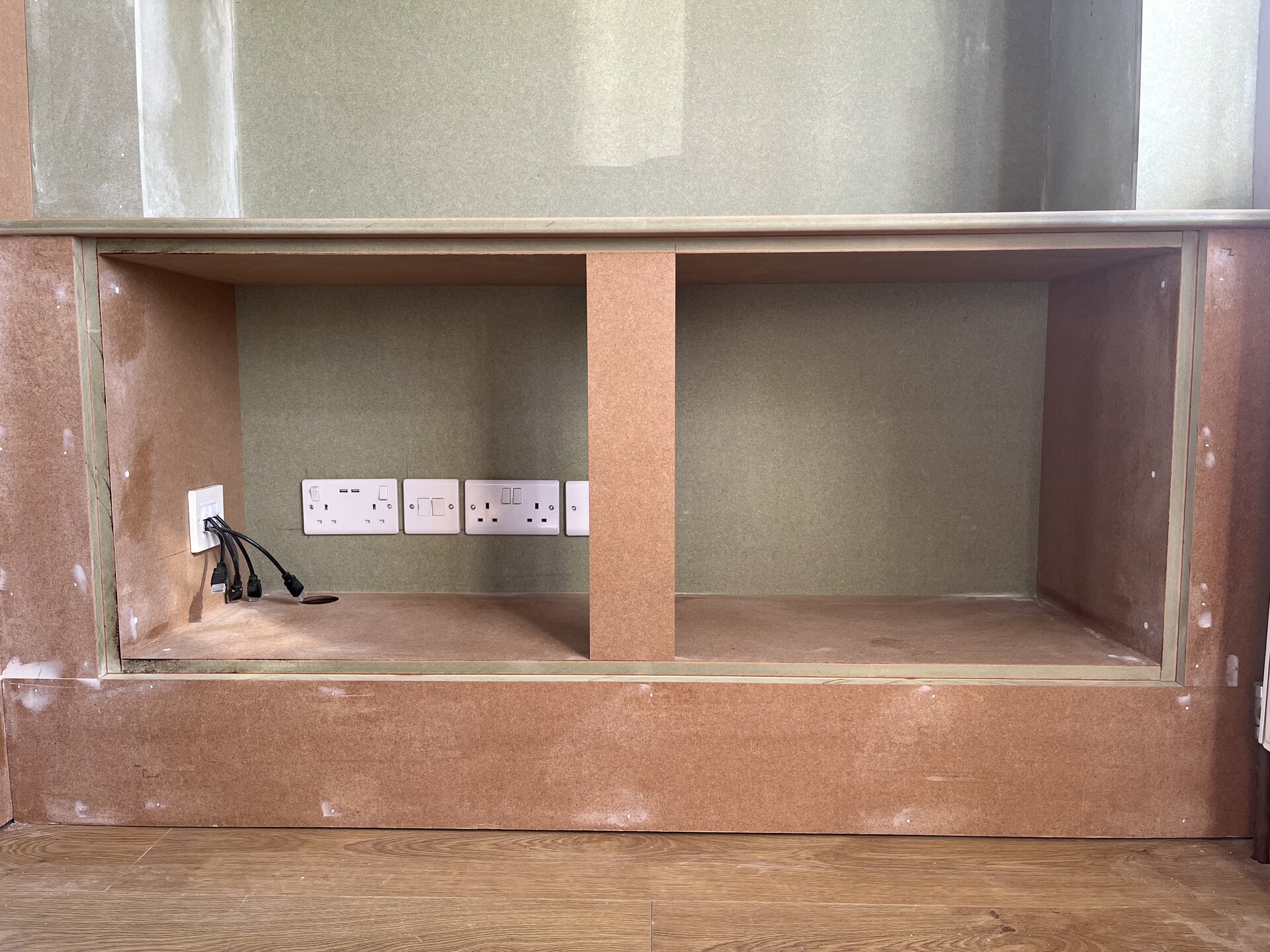 Lower cabinet boxed out in MDF with sockets and cable-management port in Sawtry media wall