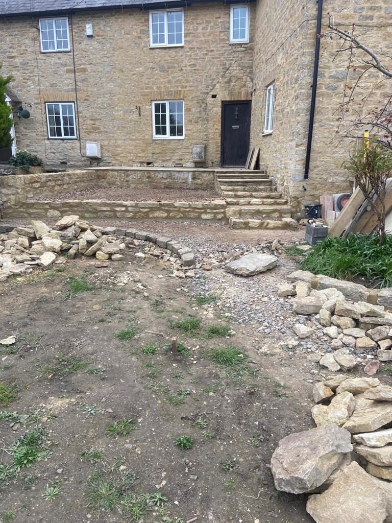 Tired front of period cottage with bare ground and rubble before garden renovation in Turvey, Bedfordshire