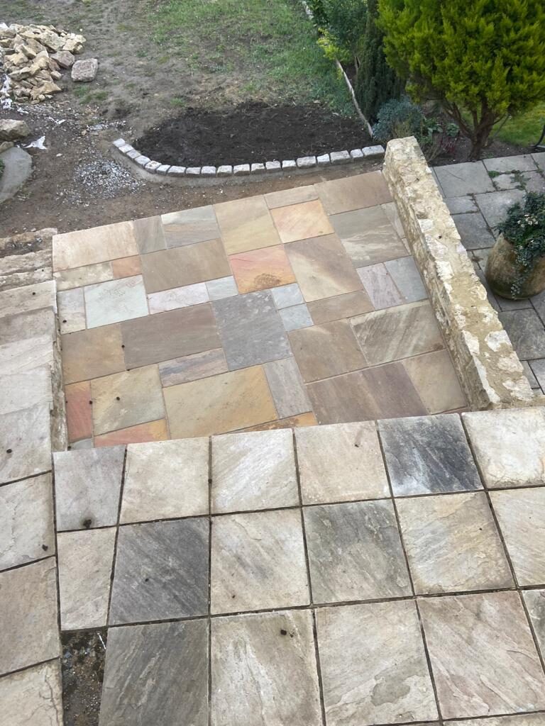Overhead detail of reclaimed sandstone patio with cobble border and curved stone wall in Turvey, Bedfordshire