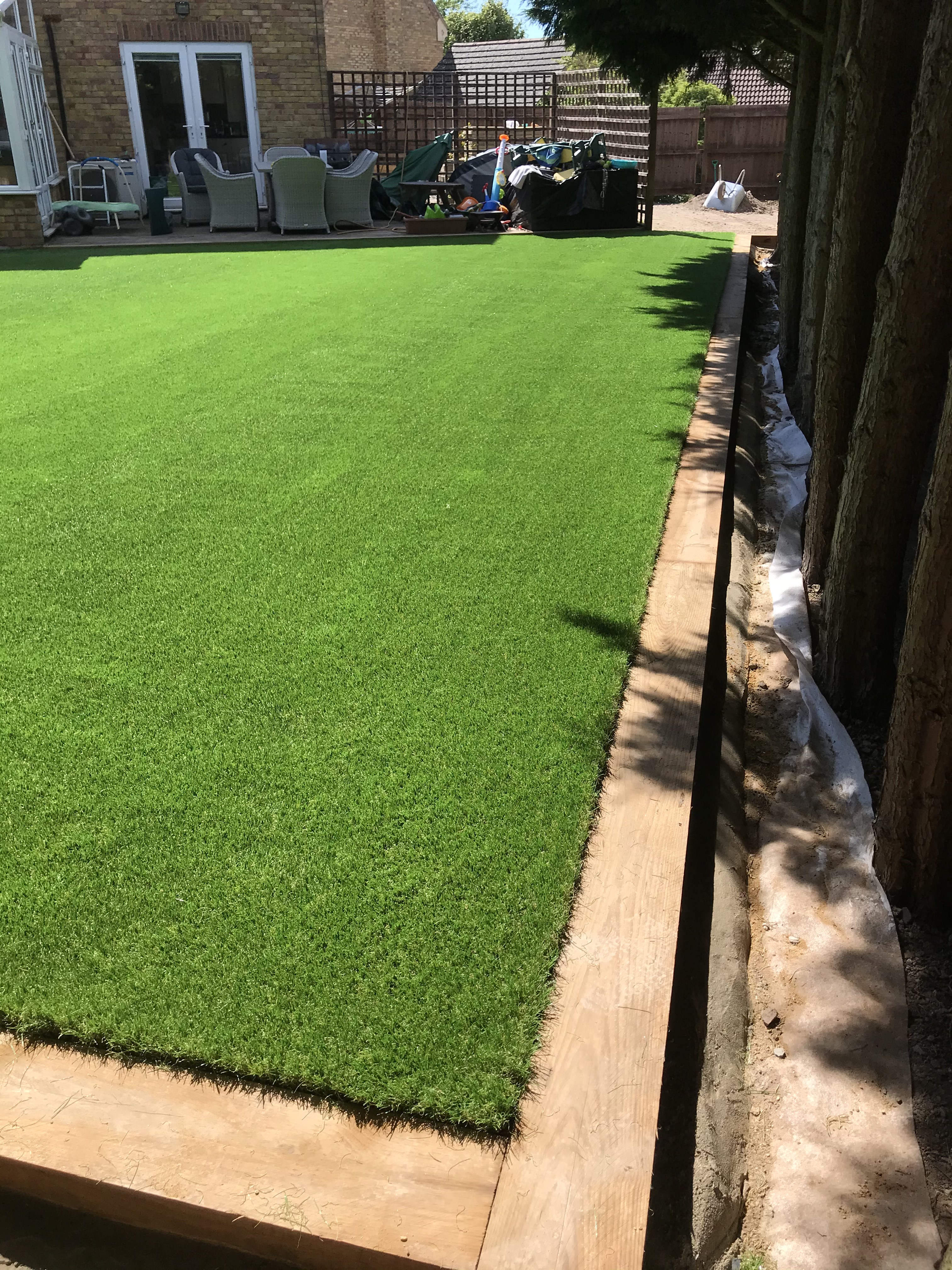 Finished premium artificial grass lawn with timber sleeper edging in Turvey, Bedfordshire
