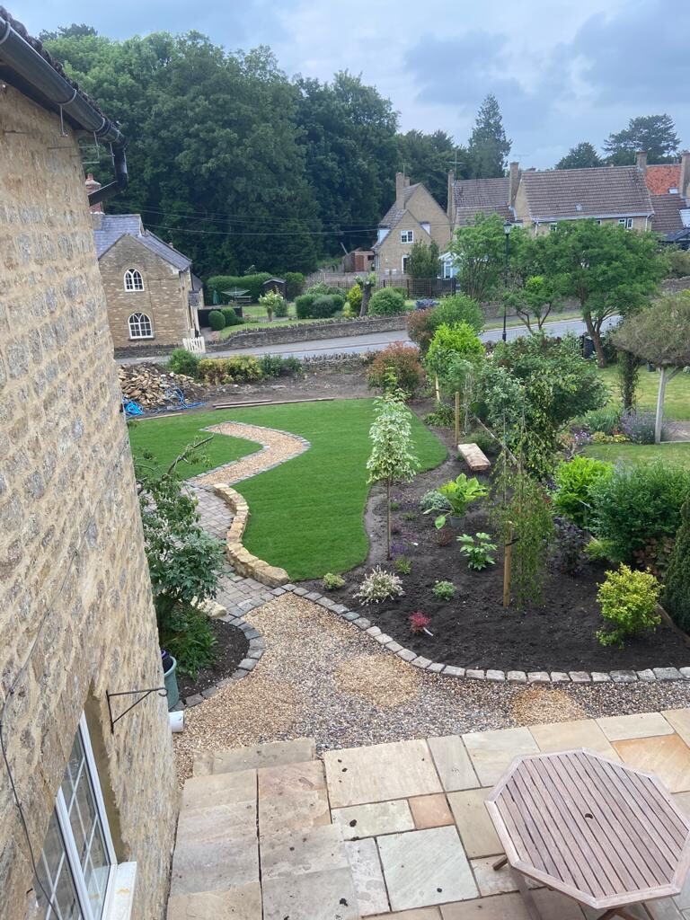Aerial view of finished rear garden with curved lawn, gravel path, cobble edging, planting beds and sandstone patio in Turvey, Bedfordshire