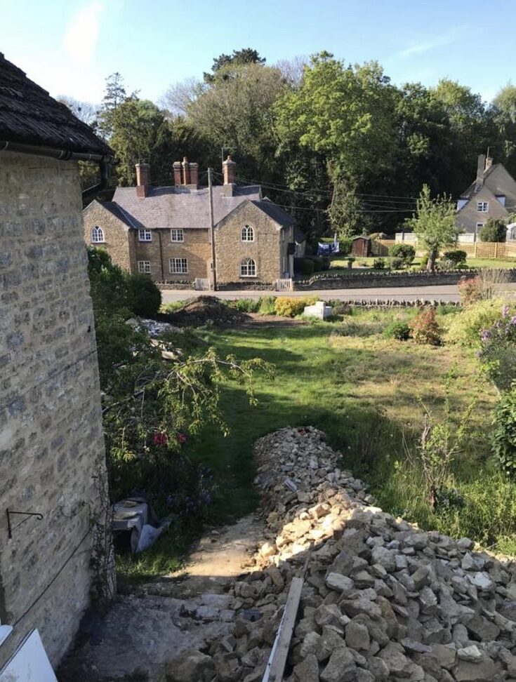 View from cottage looking across overgrown garden and rubble heap towards village in Turvey, Bedfordshire, before renovation