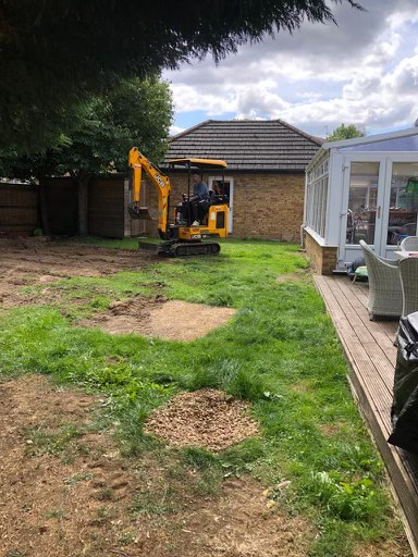 Mini digger stripping back old turf for artificial grass installation in Turvey, Bedfordshire