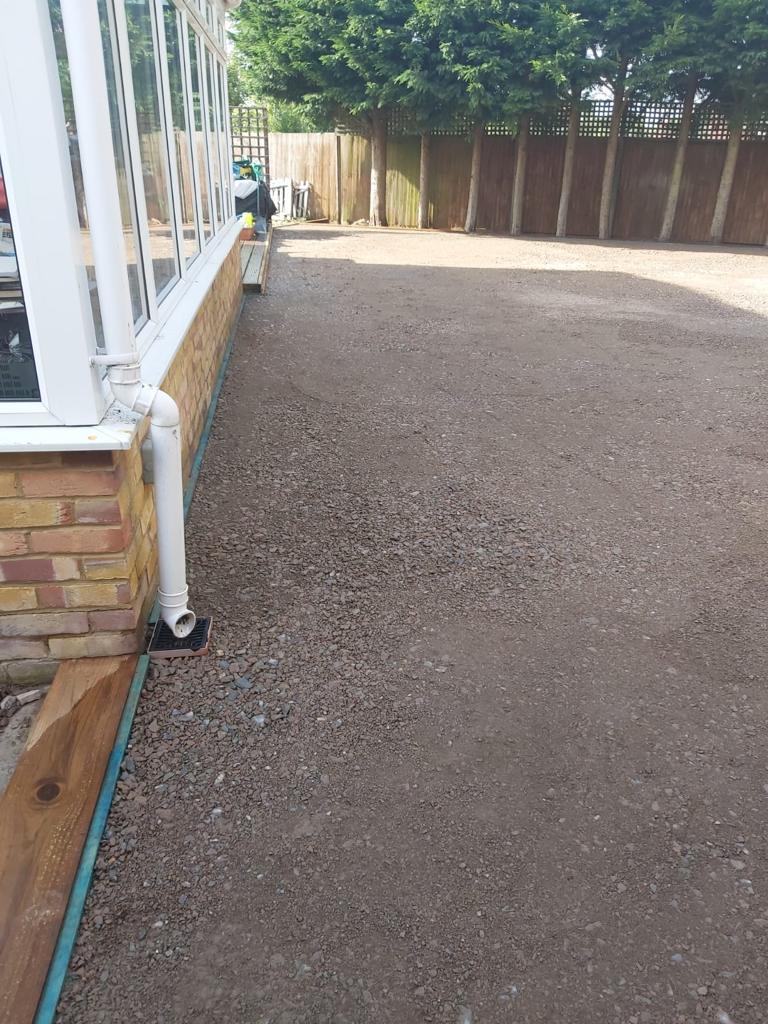 Engineered sub-base laid alongside conservatory ahead of artificial grass installation in Turvey