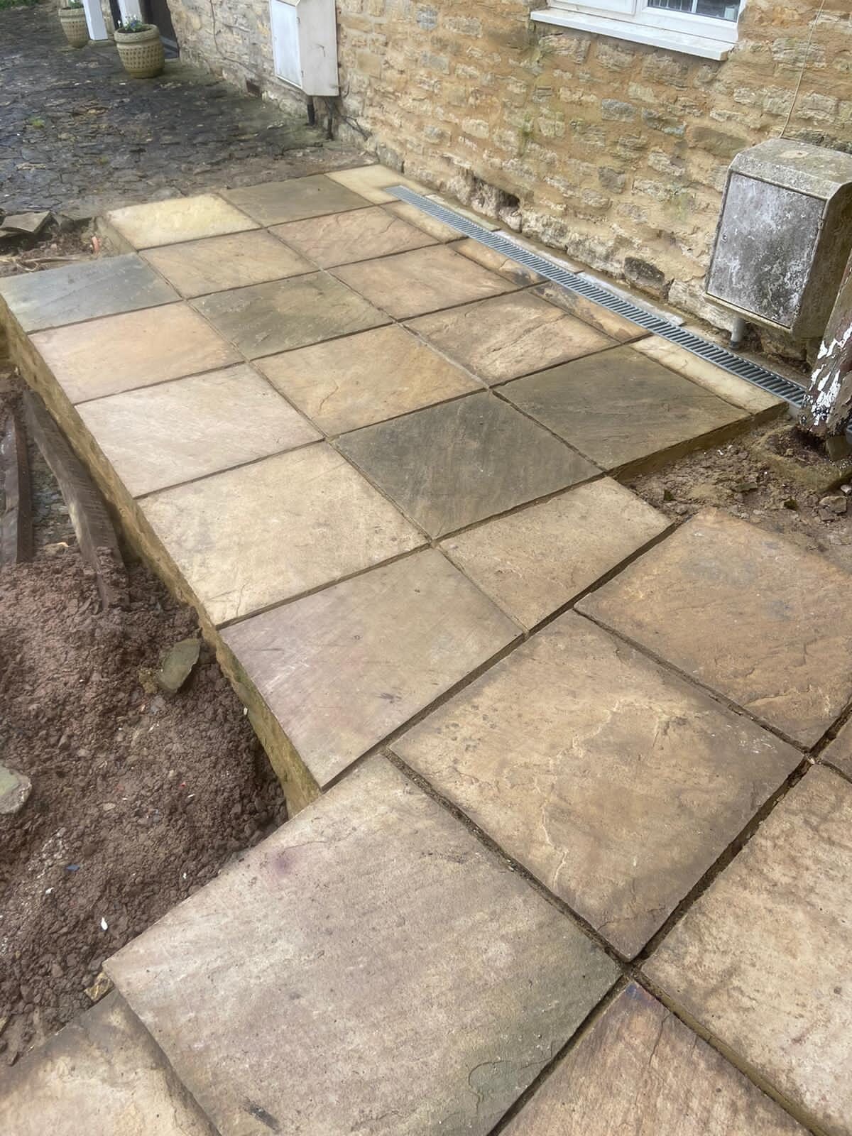 Overhead detail of mixed-tone reclaimed sandstone flags freshly laid against cottage wall in Turvey, Bedfordshire